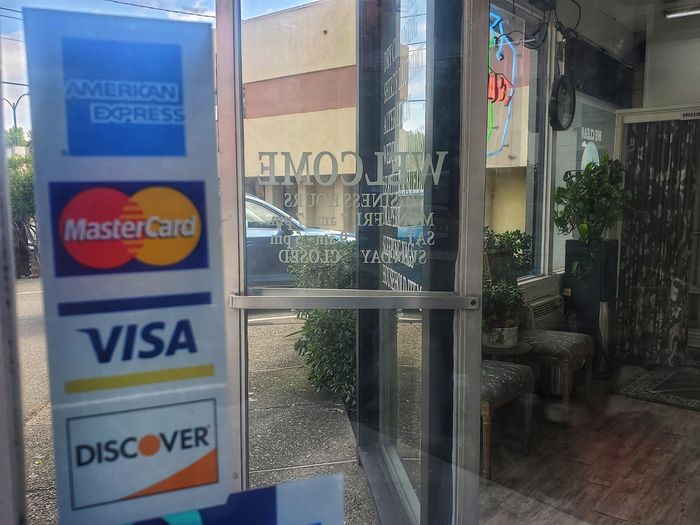 The glass front door with American Express, MasterCard, Visa and Discover decals and the welcome lettering