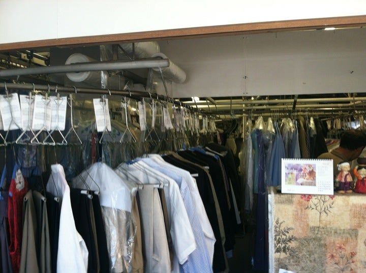 Rails of finished shirts, jackets and garments on hangers, with tagged orders hanging above the counter